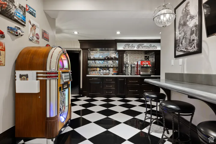 Community bar area with recessed lighting, light countertops, and dark brown cabinetry