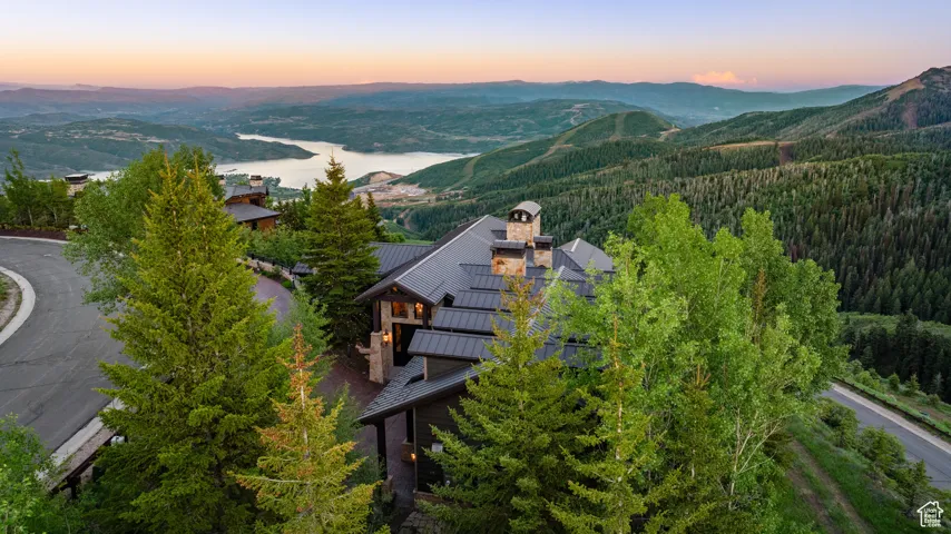 Aerial view of property and surrounding area with a forest and a water and mountain view