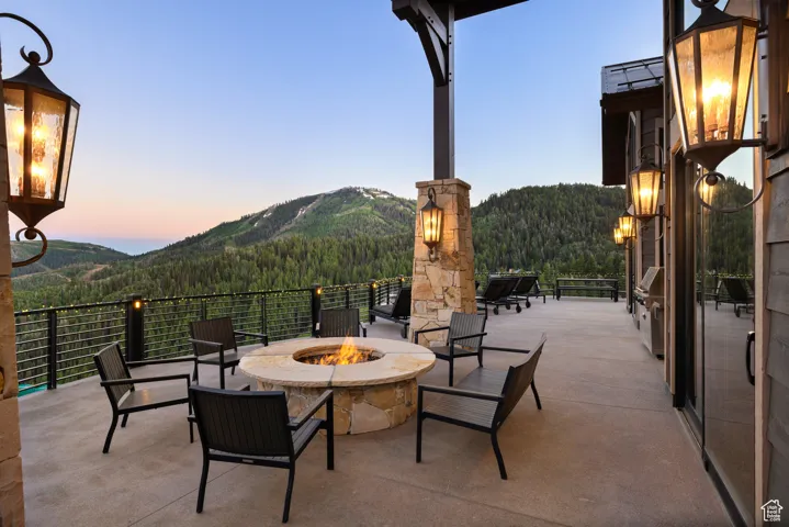 View of patio / terrace featuring an outdoor fire pit, a mountain view, and a forest view