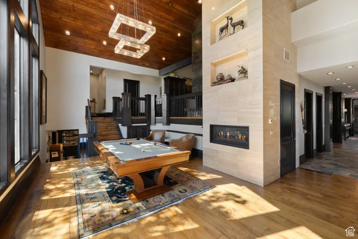 Recreation room featuring recessed lighting, hardwood / wood-style flooring, a fireplace, wood ceiling, and a high ceiling