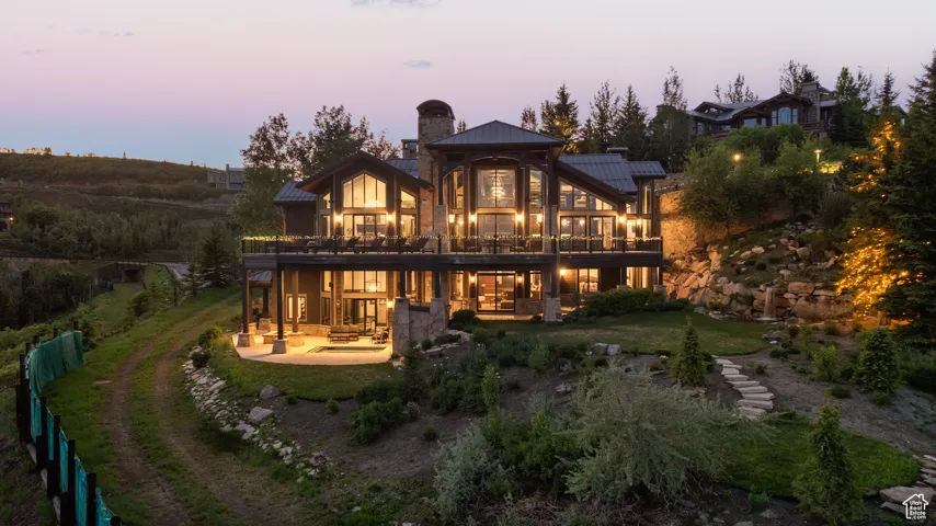 Back of property at dusk with a chimney, a patio, a metal roof, a standing seam roof, and a yard