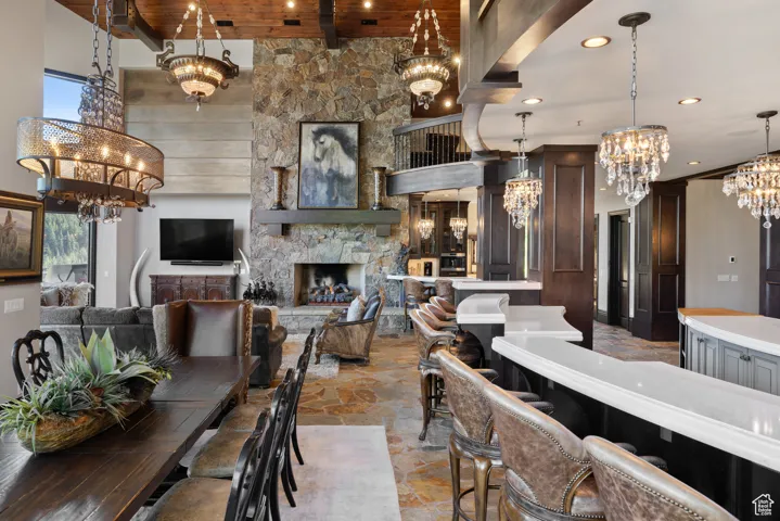 Dining area with a chandelier, a fireplace, stone tile floors, recessed lighting, and a high ceiling