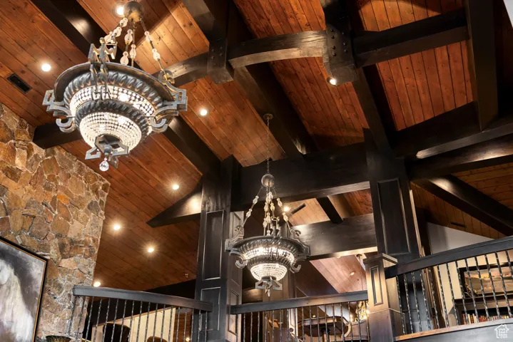 Detailed view of a chandelier, a wood ceiling with exposed beams, and recessed lighting
