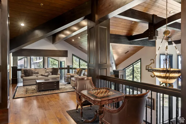 Living area featuring a chandelier, wood-type flooring, high vaulted ceiling, and a wooden ceiling with exposed beams