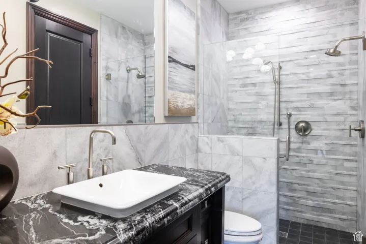 Full bath featuring tile walls, a stall shower, vanity, and tasteful backsplash
