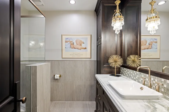 Bathroom featuring vanity, a wainscoted wall, recessed lighting, and tile walls