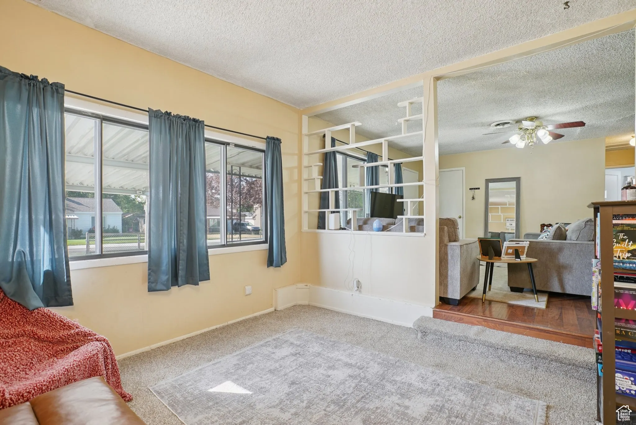 Carpeted living area featuring a textured ceiling and ceiling fan