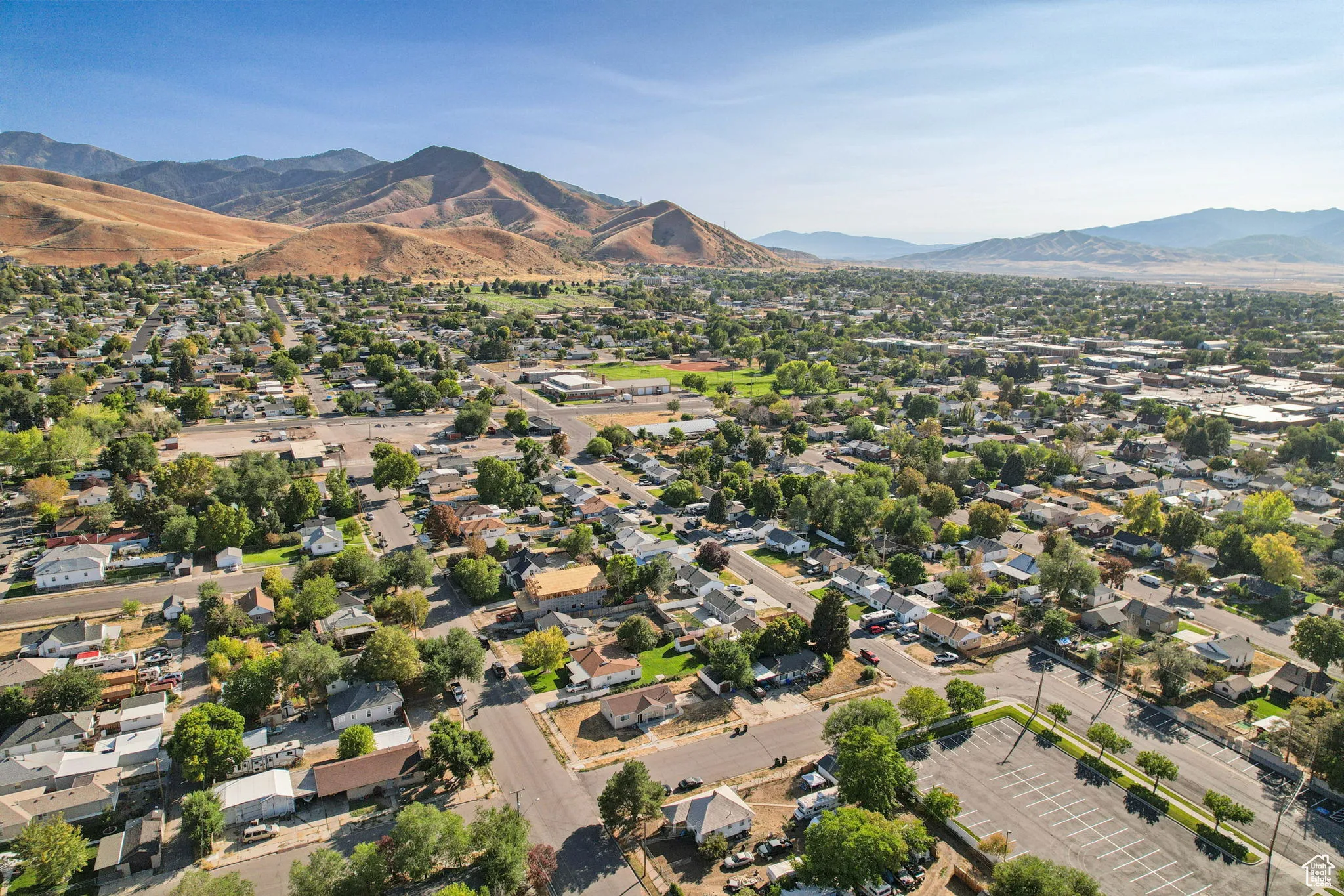 Aerial view of property and surrounding area with a mountainous background and nearby suburban area