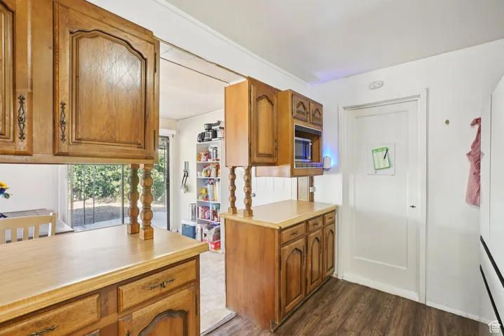 Kitchen with light countertops, brown cabinets, dark wood-style flooring, and fridge