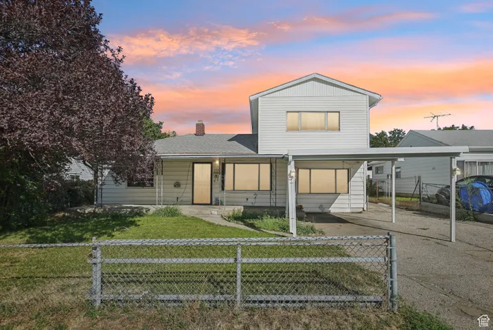 View of front facade featuring a fenced front yard, a chimney, an attached carport, and covered porch