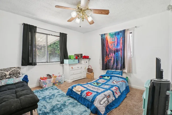 Bedroom with carpet, a textured ceiling, and a ceiling fan