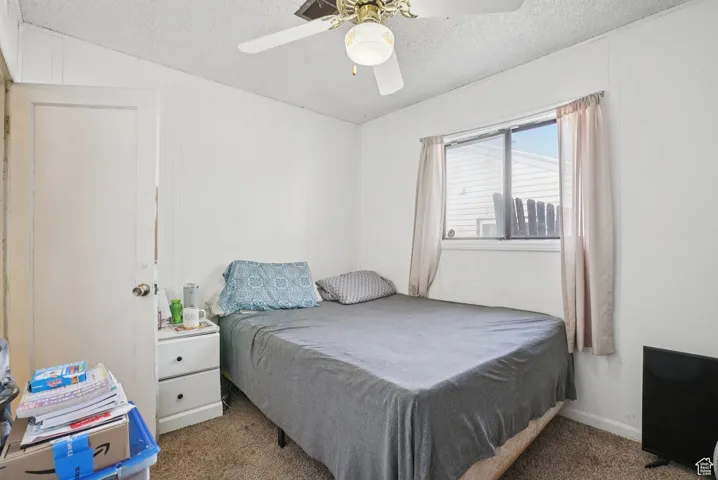 Bedroom featuring carpet flooring, a textured ceiling, and a ceiling fan