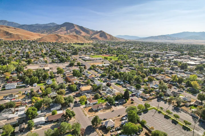 Aerial view of property and surrounding area with a mountainous background and nearby suburban area