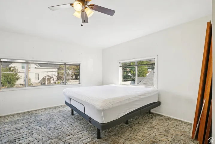 Carpeted bedroom featuring ceiling fan and baseboards