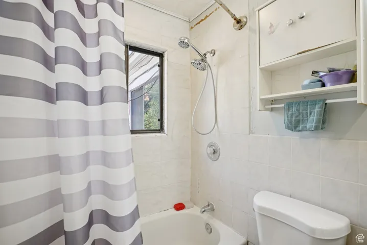 Full bathroom with shower / tub combo and tile walls