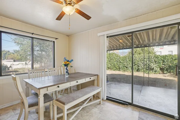 Dining space with wooden walls, plenty of natural light, and ceiling fan