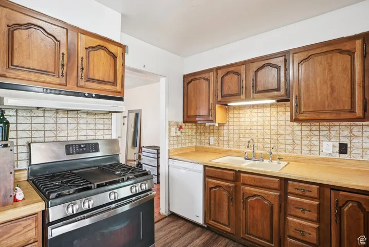 Kitchen featuring gas stove, brown cabinetry, light countertops, and dishwasher