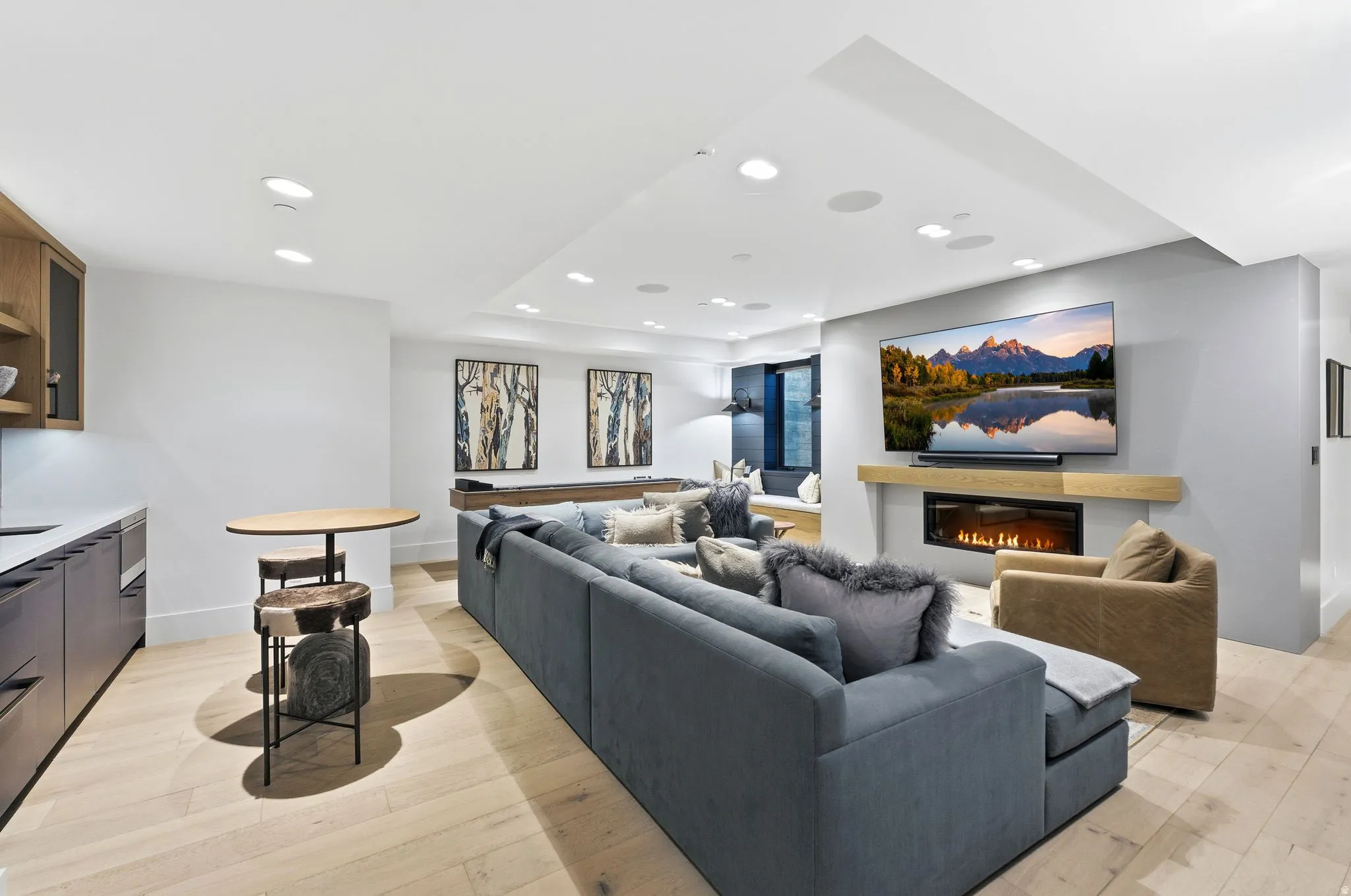 Living area with recessed lighting, a glass covered fireplace, and light wood finished floors