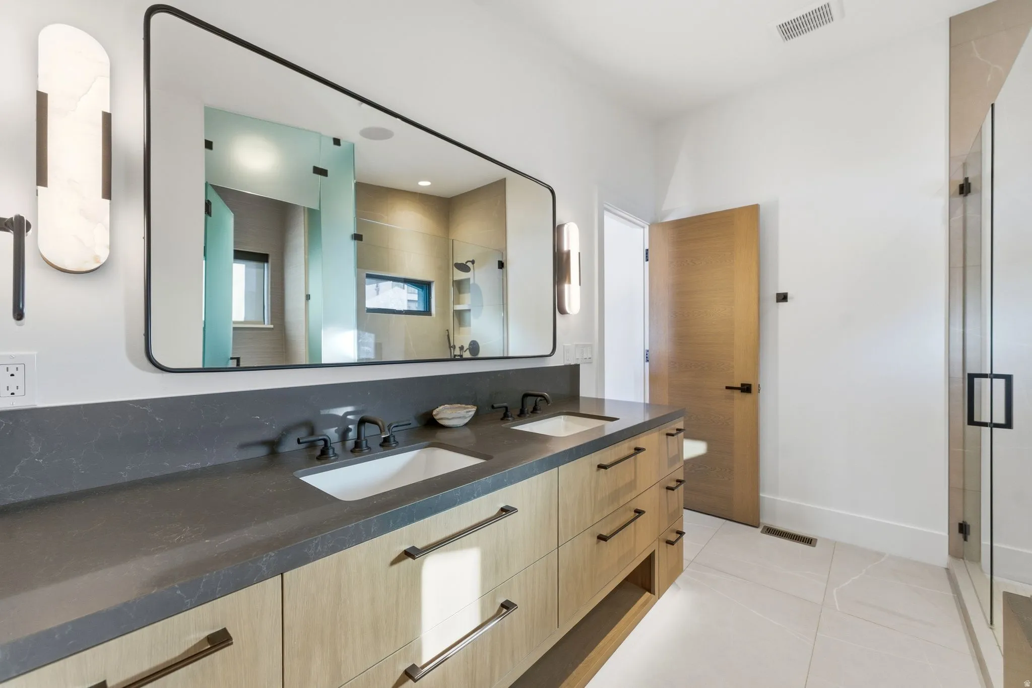 Full bath with double vanity, light tile patterned floors, and a stall shower