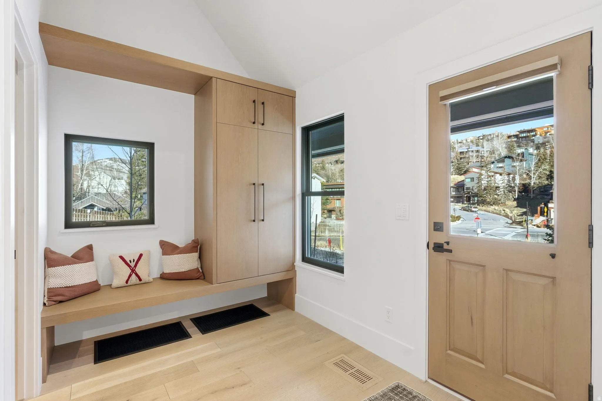 Mudroom featuring light wood finished floors and vaulted ceiling