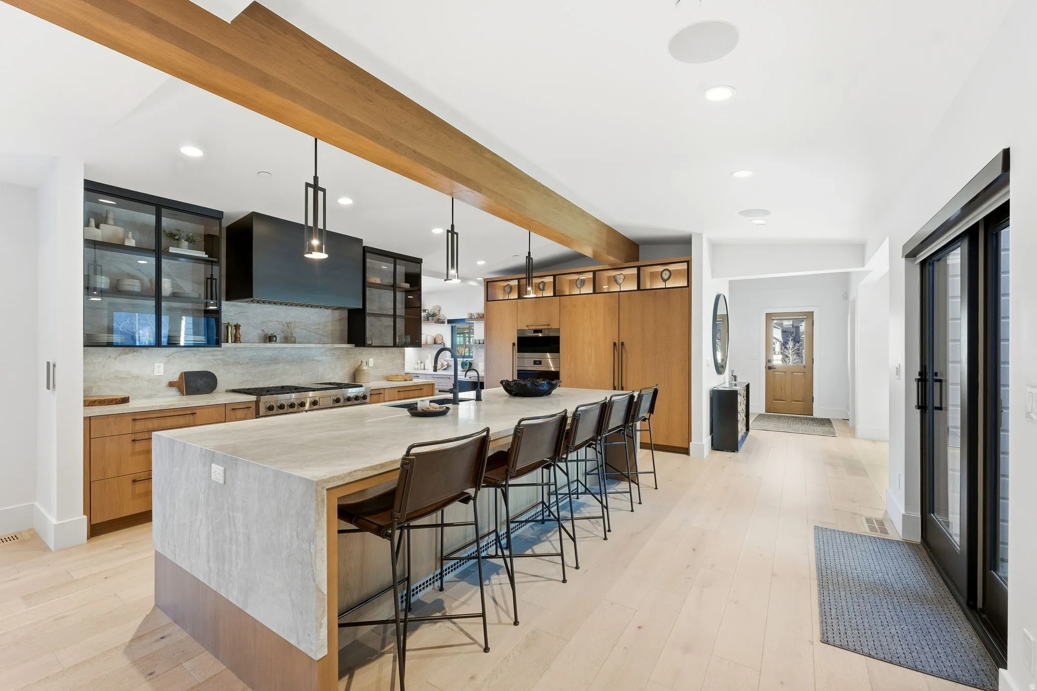 Kitchen featuring a breakfast bar, decorative backsplash, glass insert cabinets, pendant lighting, and light stone counters