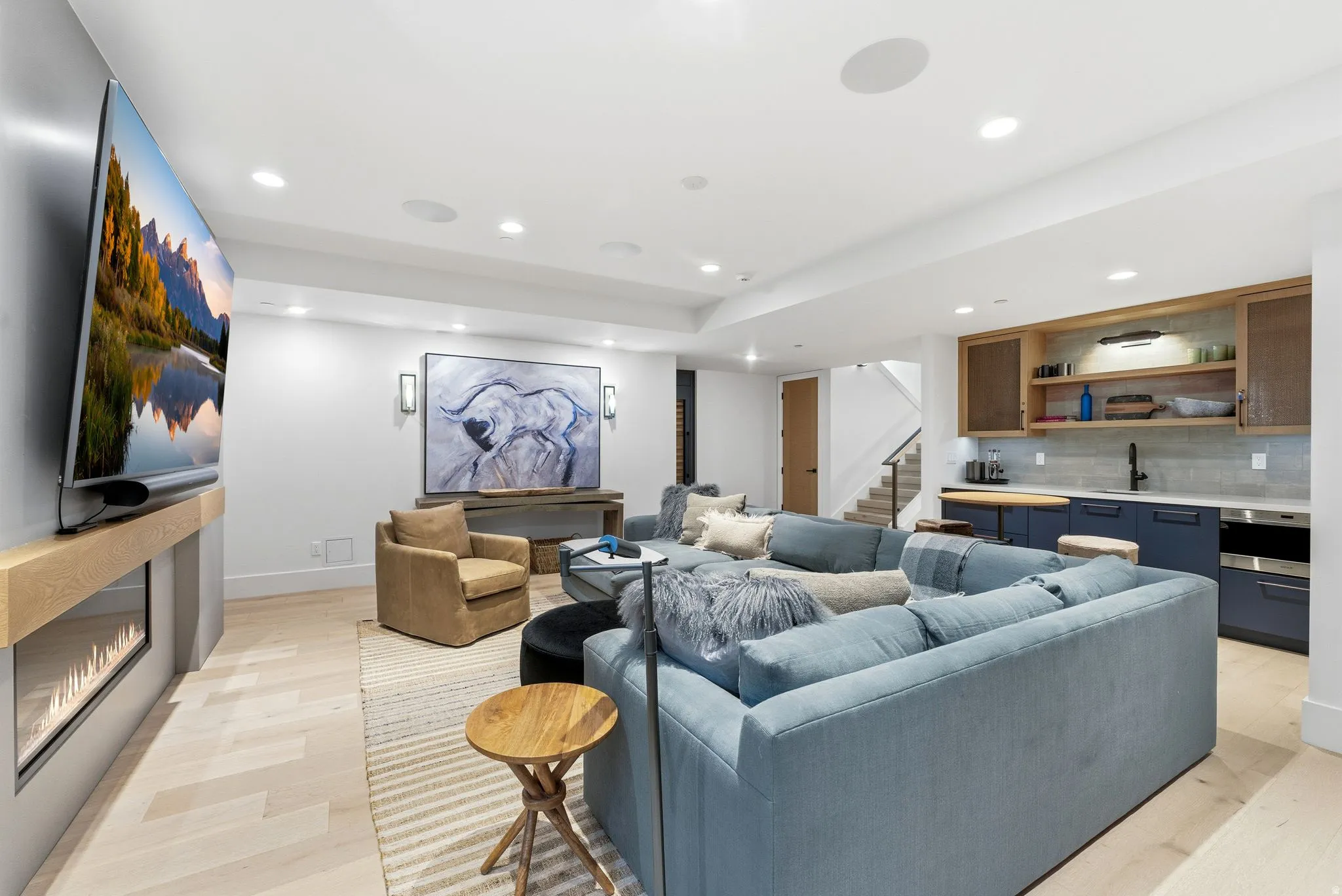 Living area with recessed lighting, wet bar, stairway, light wood finished floors, and a glass covered fireplace
