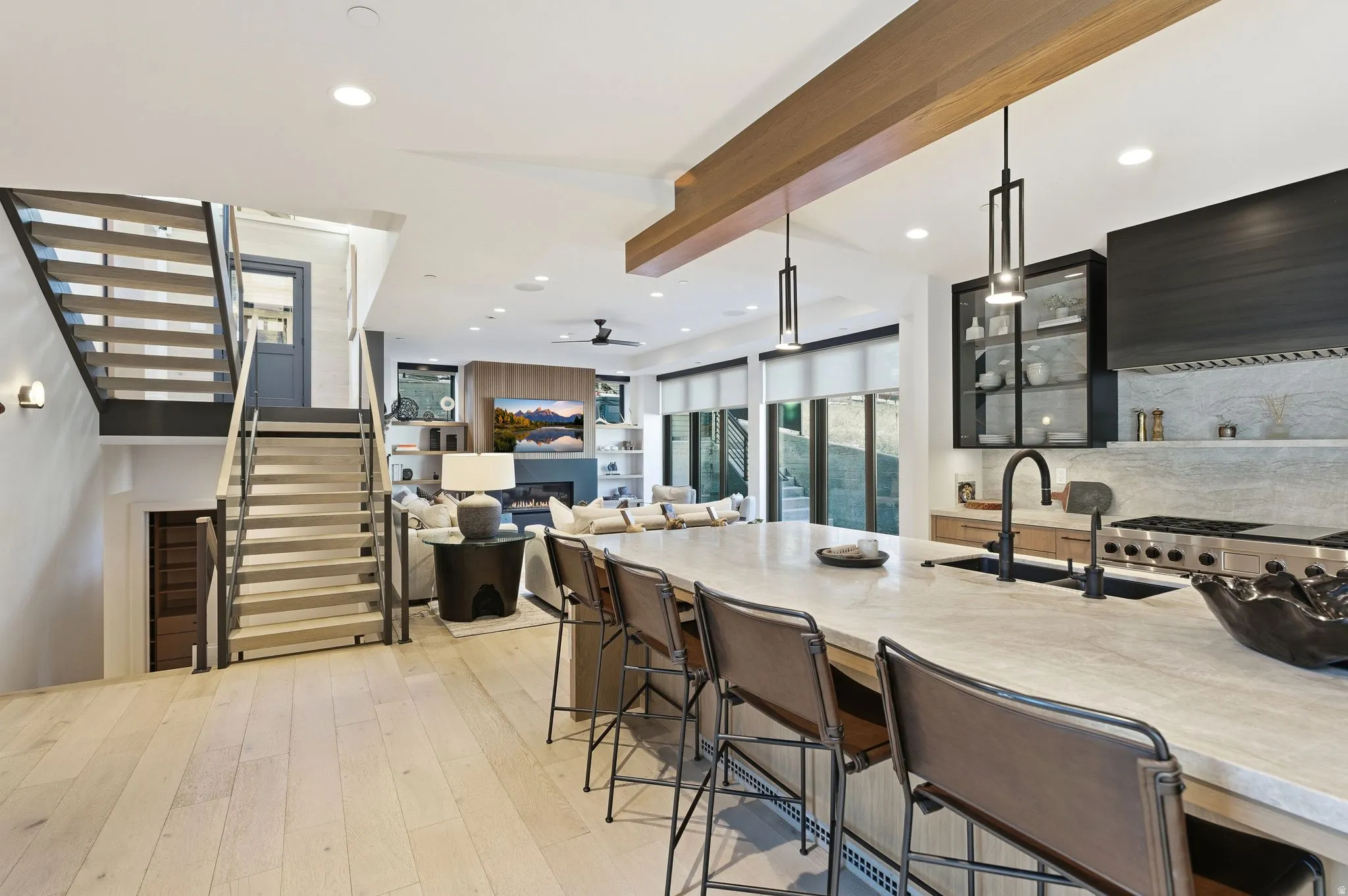 Kitchen featuring decorative light fixtures, glass insert cabinets, light wood-style flooring, tasteful backsplash, and a kitchen bar