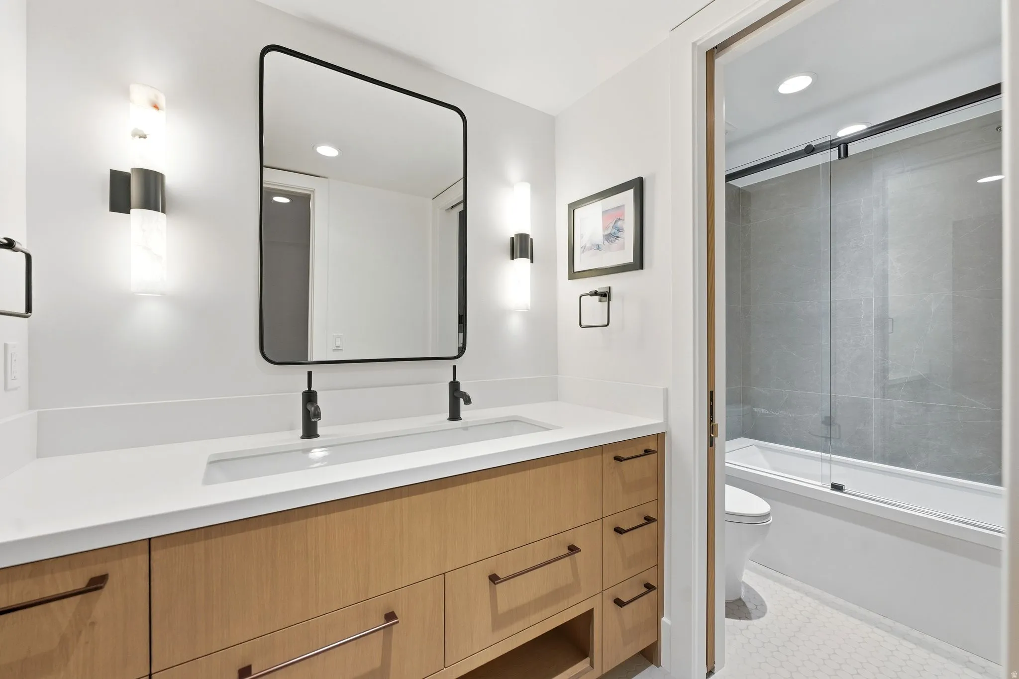 Bathroom with double vanity, shower / bath combination with glass door, and recessed lighting
