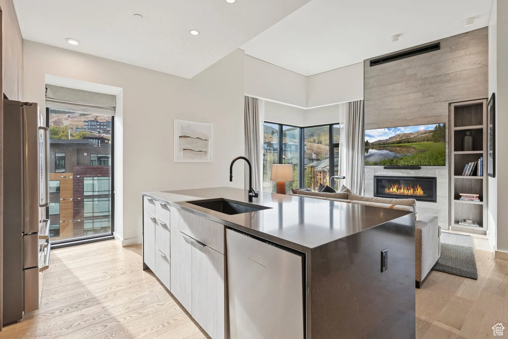 Kitchen with modern cabinets, stainless steel appliances, light wood-style floors, open floor plan, and dark stone counters
