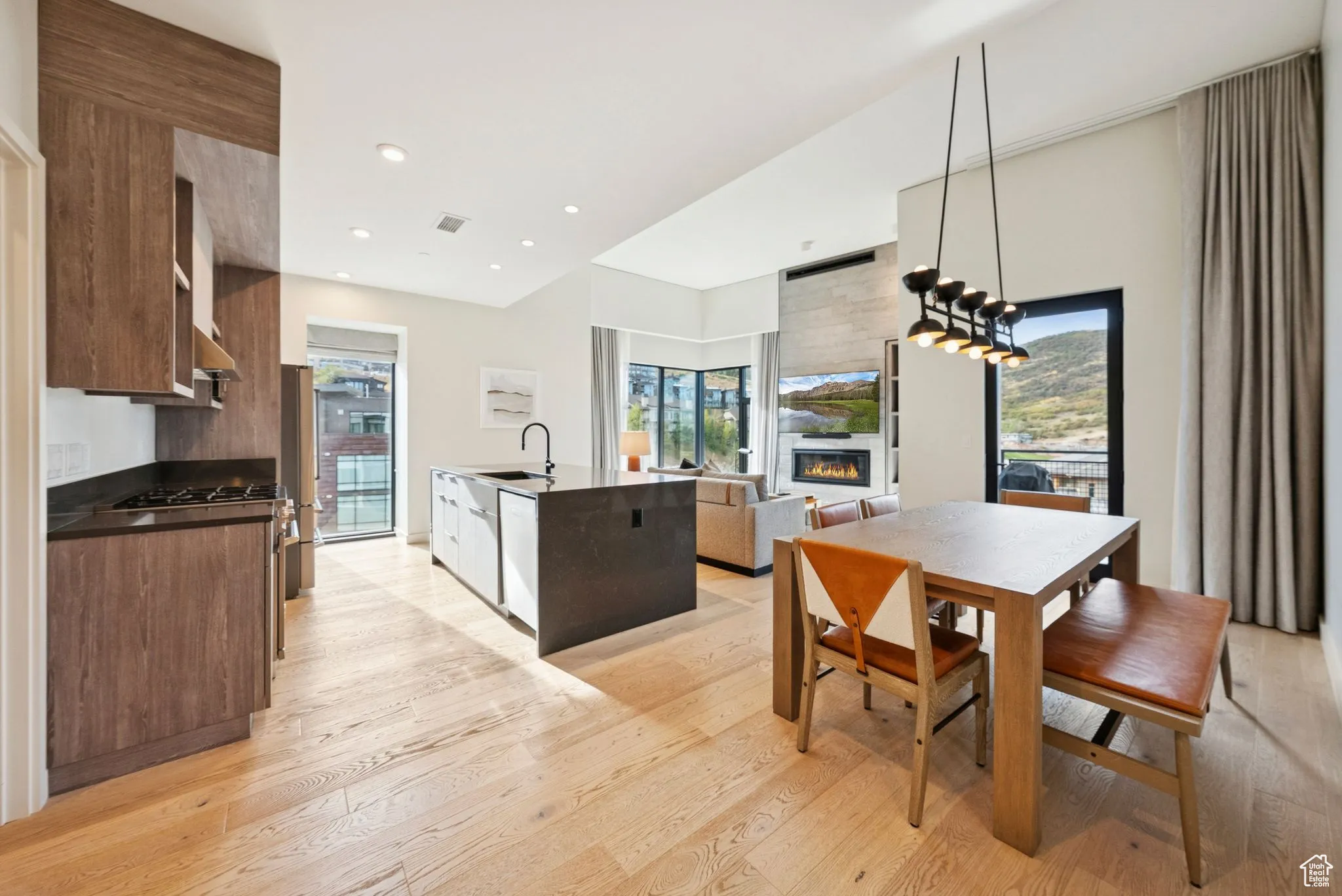 Dining space featuring a large fireplace, light wood-style flooring, recessed lighting, and a chandelier