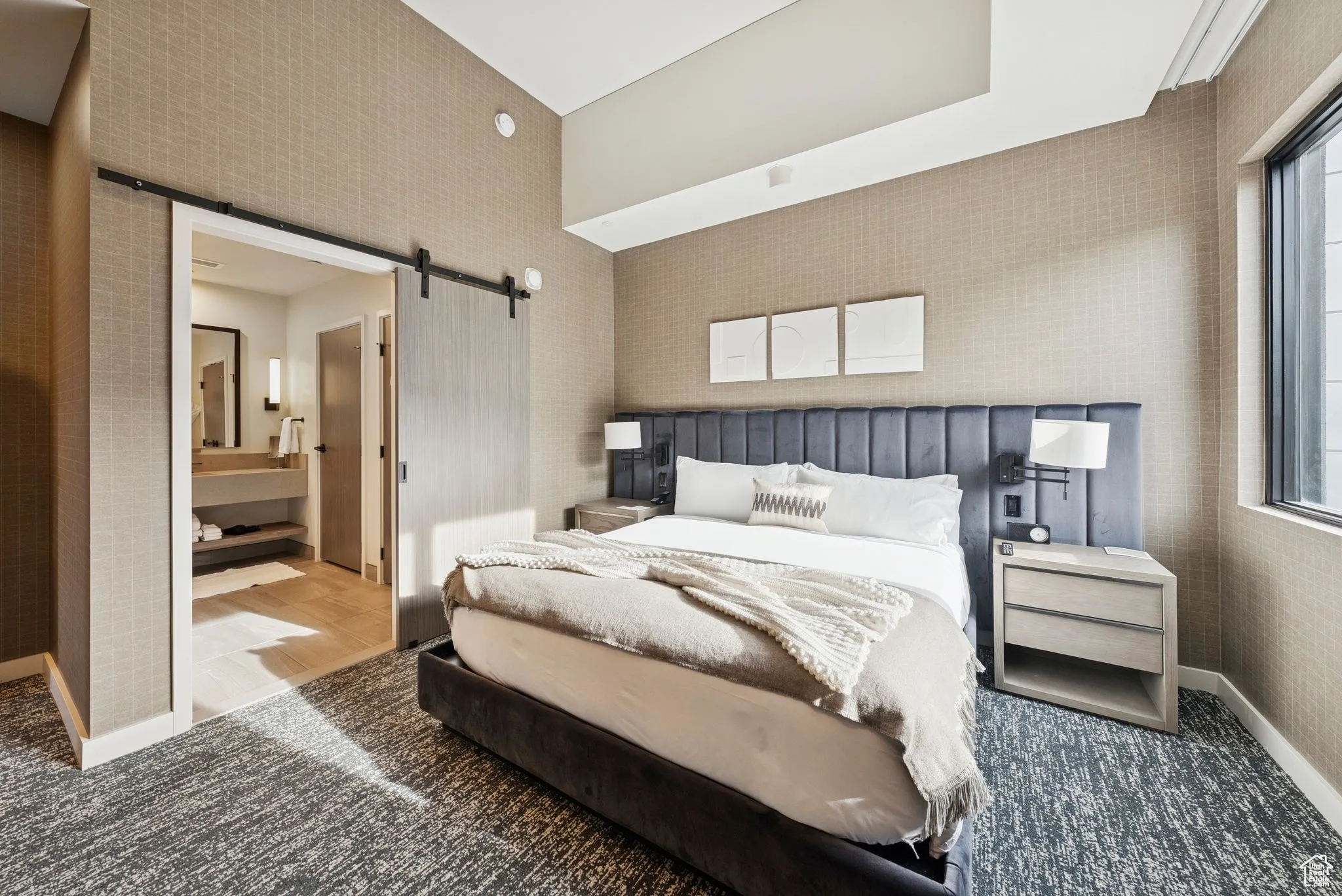 Carpeted bedroom with a barn door and ensuite bathroom