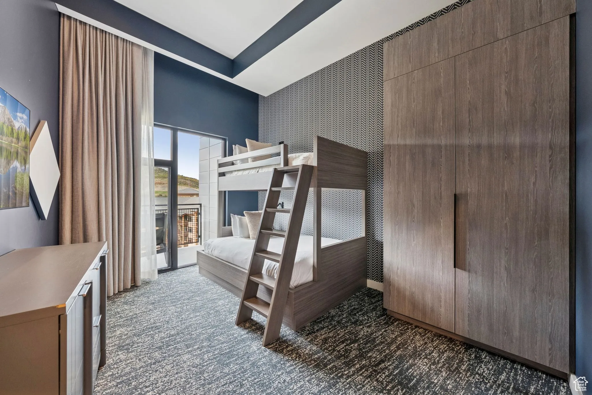 Bedroom with wallpapered walls, dark colored carpet, an accent wall, and access to outside