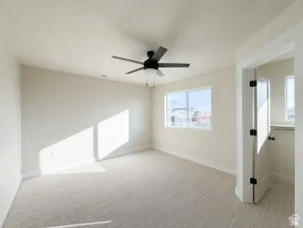 Empty room with a textured ceiling, light carpet, and ceiling fan