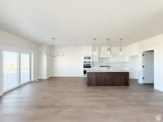 Kitchen with open floor plan, light countertops, white cabinets, a center island with sink, and extractor fan