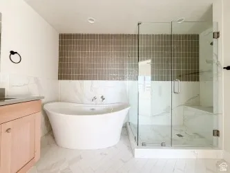 Full bath with vanity, a marble finish shower, tile walls, and a freestanding bath
