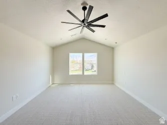 Spare room with light carpet, vaulted ceiling, ceiling fan, and a textured ceiling