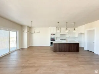 Kitchen with light countertops, open floor plan, white cabinets, and hanging light fixtures