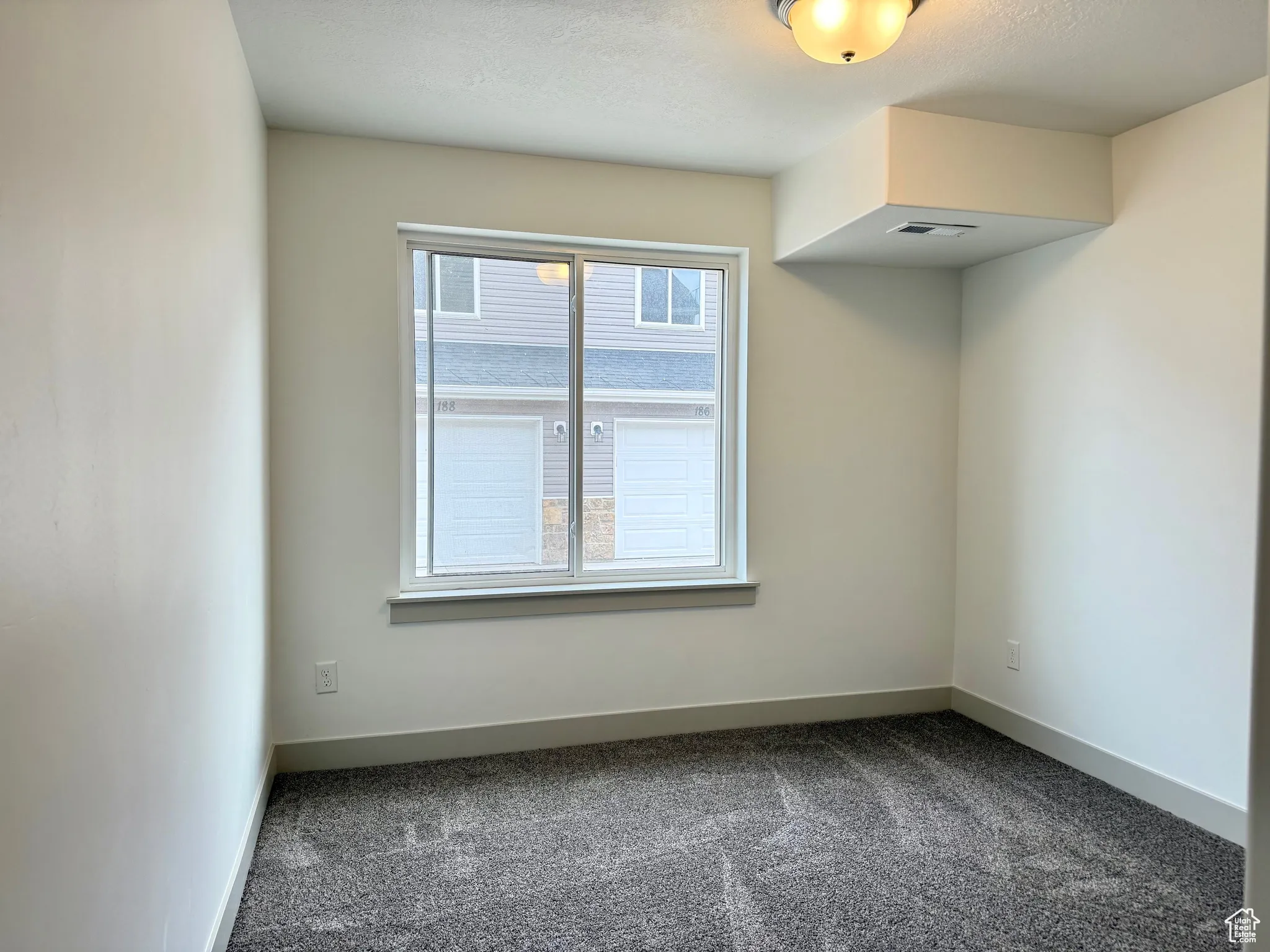 Spare room featuring dark colored carpet and baseboards