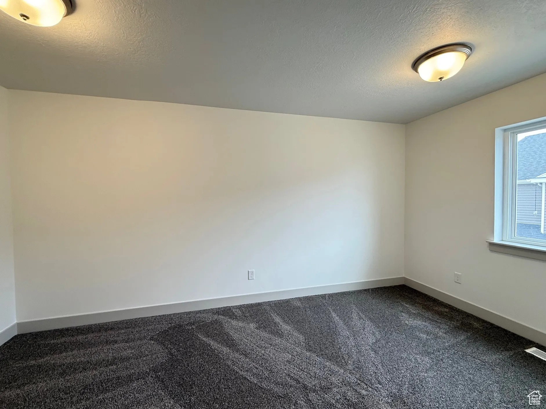 Bedroom with a textured ceiling and dark colored carpet