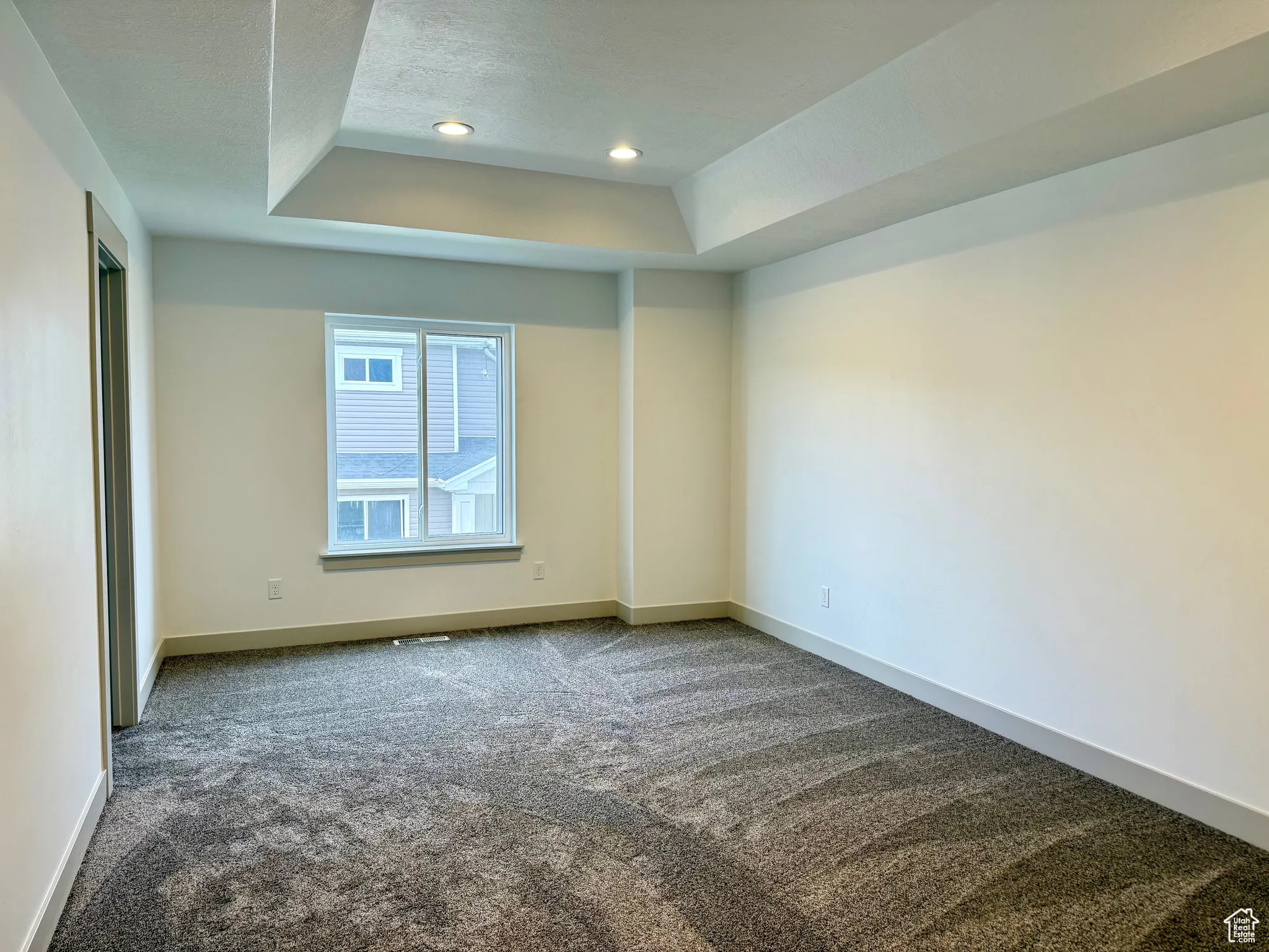 Primary bedroom with carpet, a tray ceiling, and recessed lighting