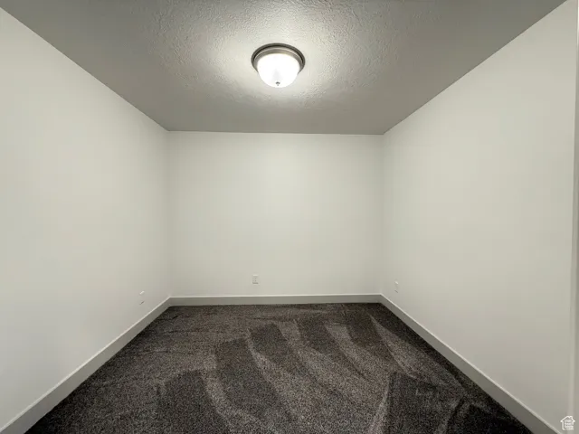 Spare room with dark carpet and a textured ceiling
