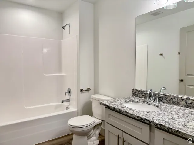 Bathroom with tub / shower combination, vanity, and dark wood-style flooring