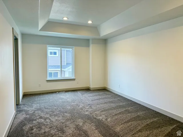 Primary bedroom with carpet, a tray ceiling, and recessed lighting