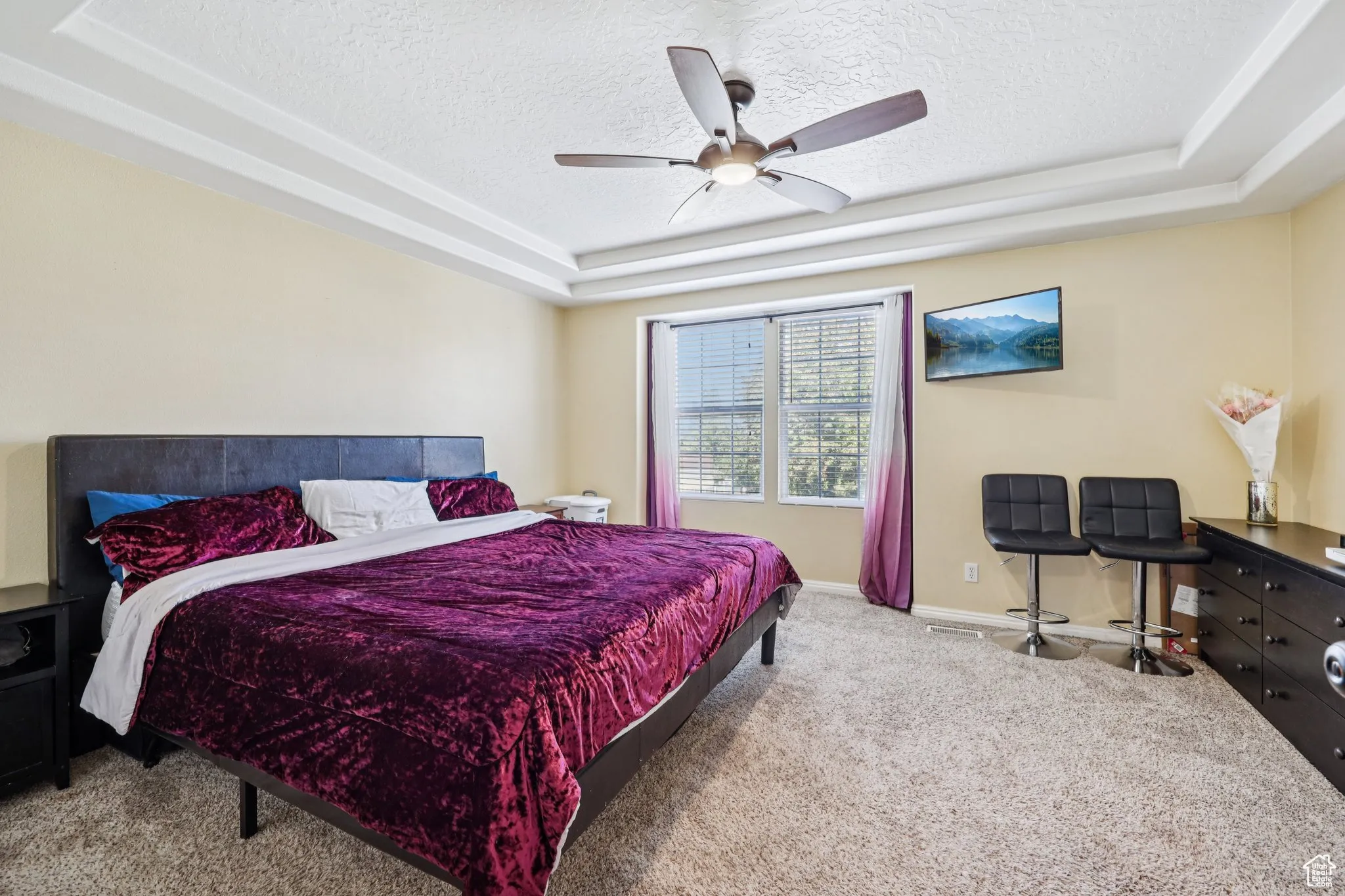 Bedroom featuring a raised ceiling, carpet flooring, a ceiling fan, and a textured ceiling