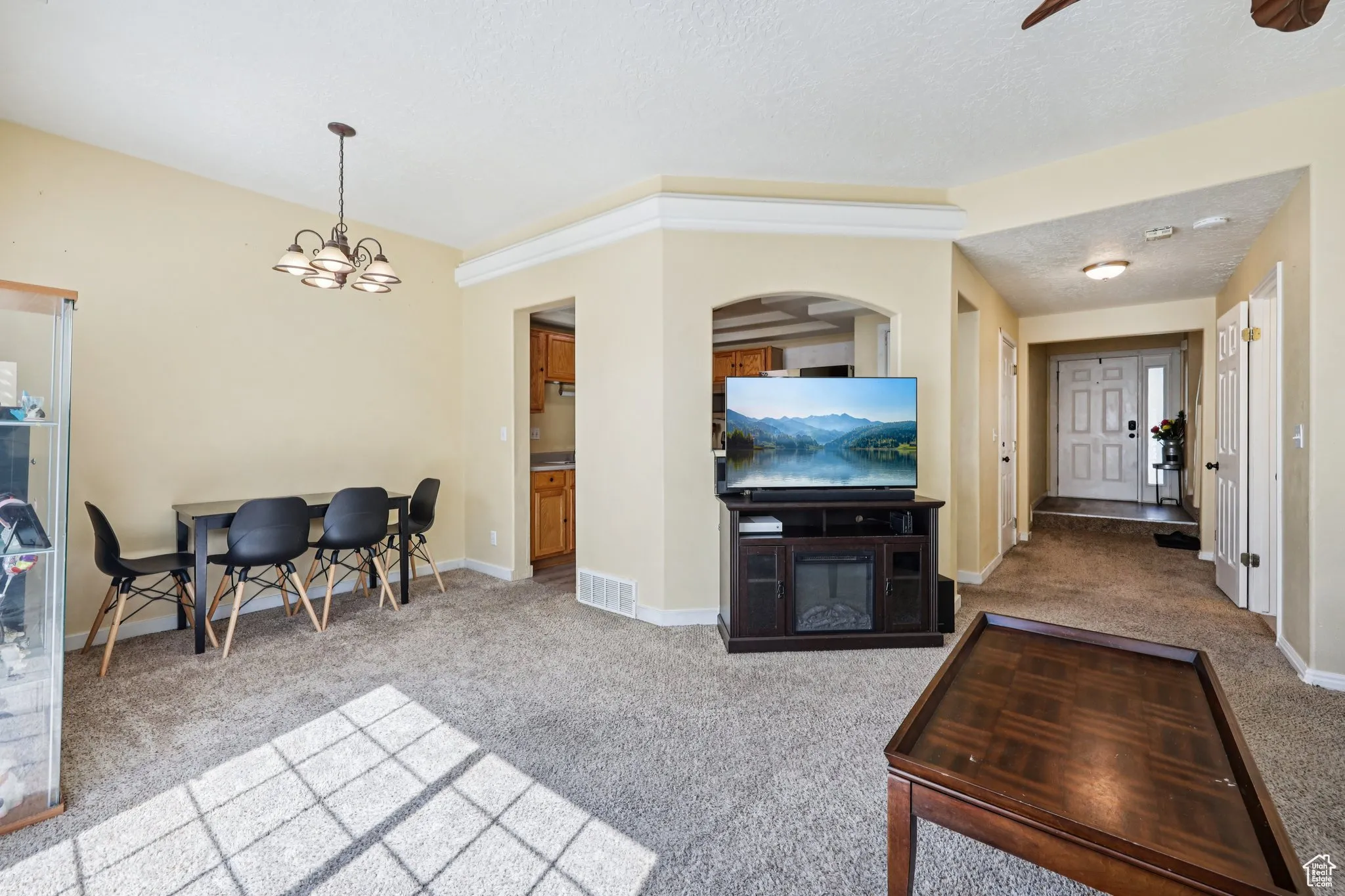 Living area featuring light carpet, a chandelier, a textured ceiling, and ceiling fan