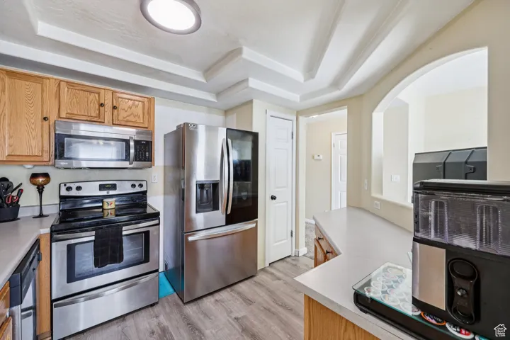 Kitchen featuring appliances with stainless steel finishes, a tray ceiling, and light countertops