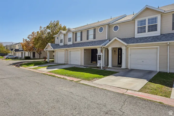 Traditional-style home with roof with shingles, concrete driveway, a garage, and a front yard
