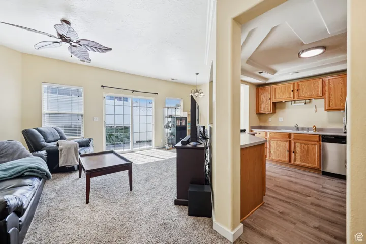 Living room featuring ceiling fan, light carpet, and a textured ceiling
