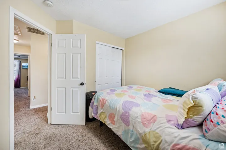 Carpeted bedroom featuring lofted ceiling, a closet, and a textured ceiling
