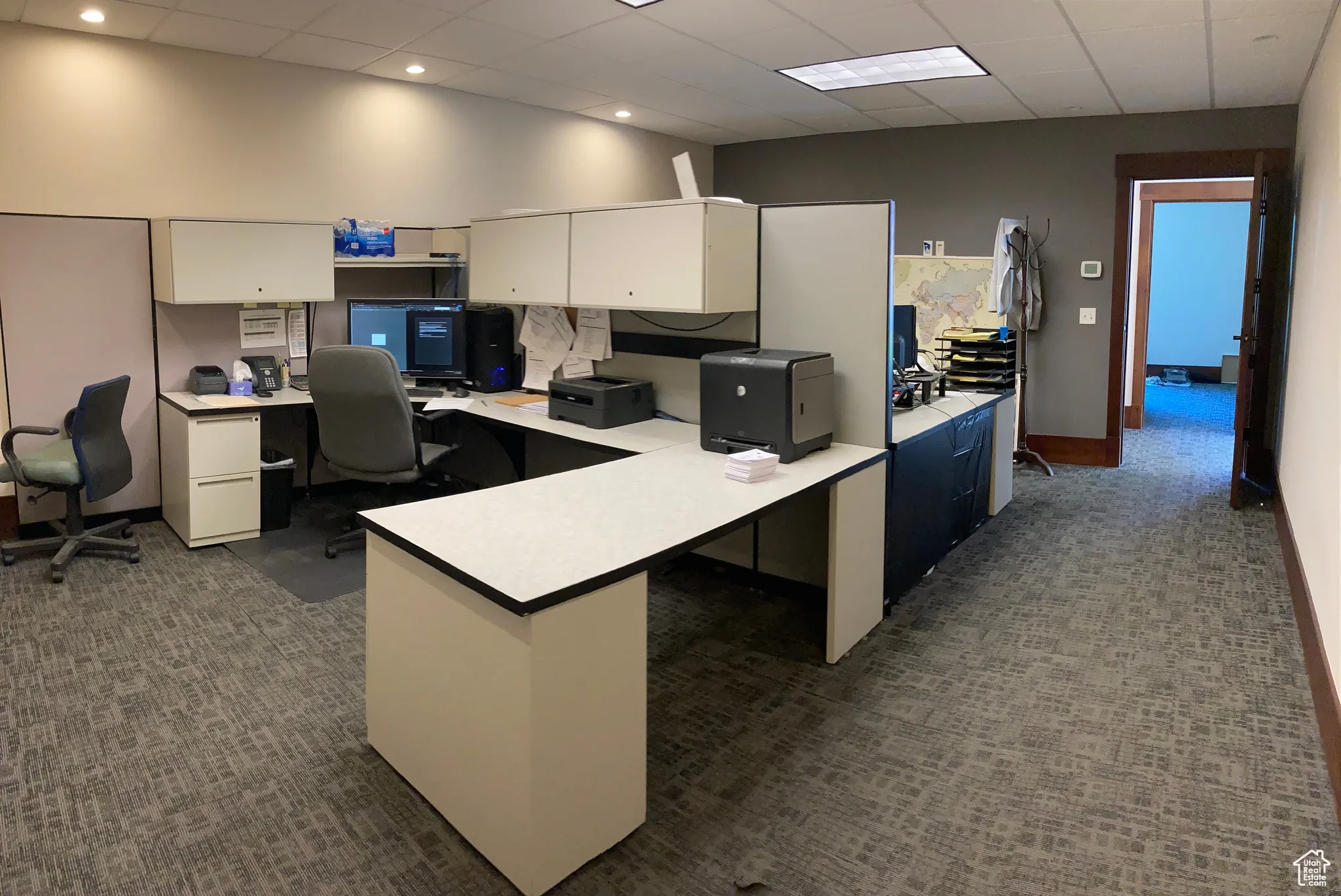 Office area with a paneled ceiling and dark colored carpet